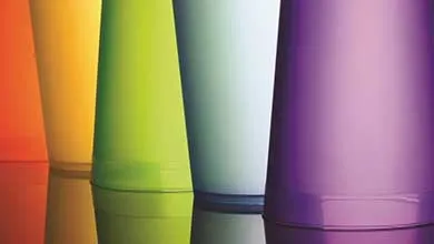 Five colorful tumblers—orange, yellow, green, light blue, and purple—lined up on a reflective surface.