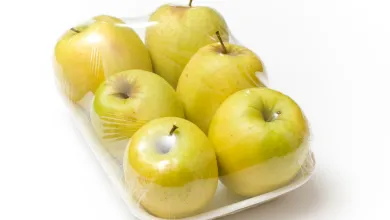 Pack of green apples wrapped in clear plastic packaging on a white background.